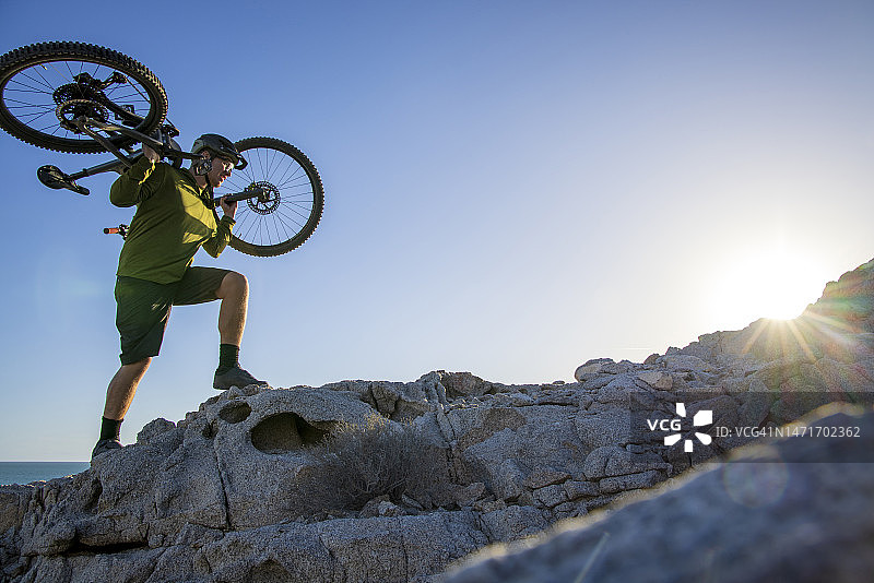 山地自行车手把自行车抬上陡峭的山脊图片素材