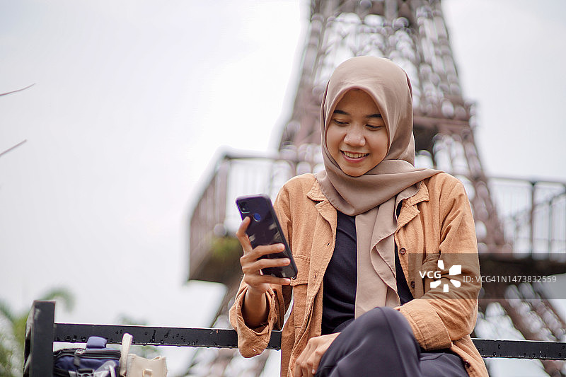 一名穆斯林女子在公园里用智能手机玩社交媒体图片素材