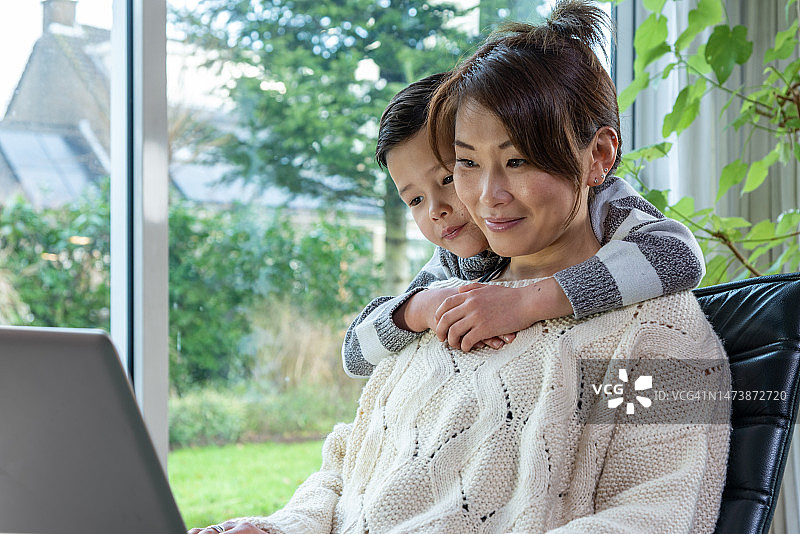 快乐的亚洲母亲和儿子在家里看着笔记本电脑图片素材