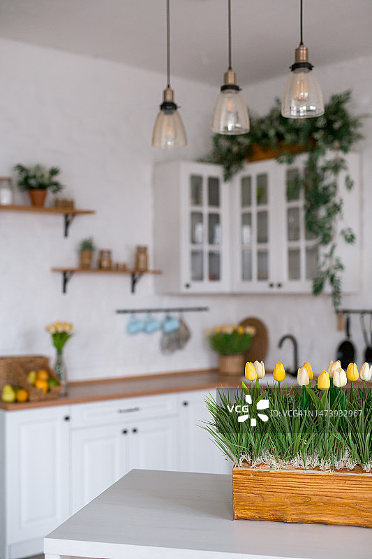 白色的桌子上放着一束郁金香。背景是斯堪的纳维亚风格的白色厨房内部。家庭舒适的概念。图片素材