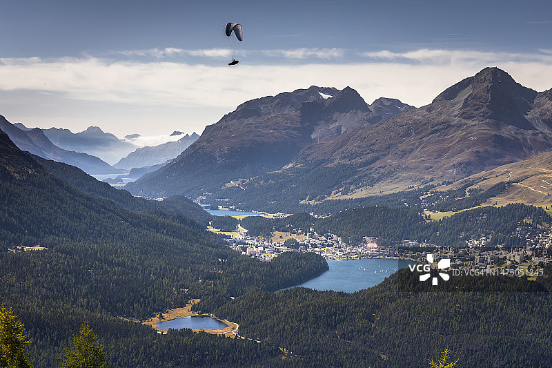 在瑞士阿尔卑斯山脉格劳宾登恩加丁山谷的穆奥塔斯·穆拉格尔乘坐滑翔伞飞越圣莫里茨湖图片素材