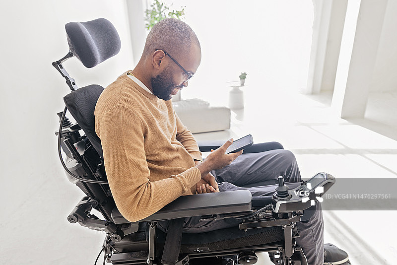 残疾黑人坐在轮椅上使用智能手机图片素材