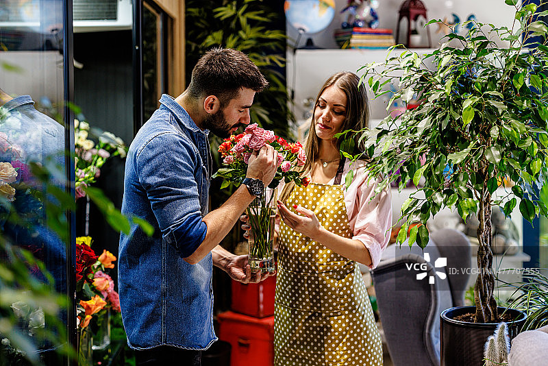 一对年轻夫妇在花店欣赏气味鲜艳的花朵的肖像。图片素材