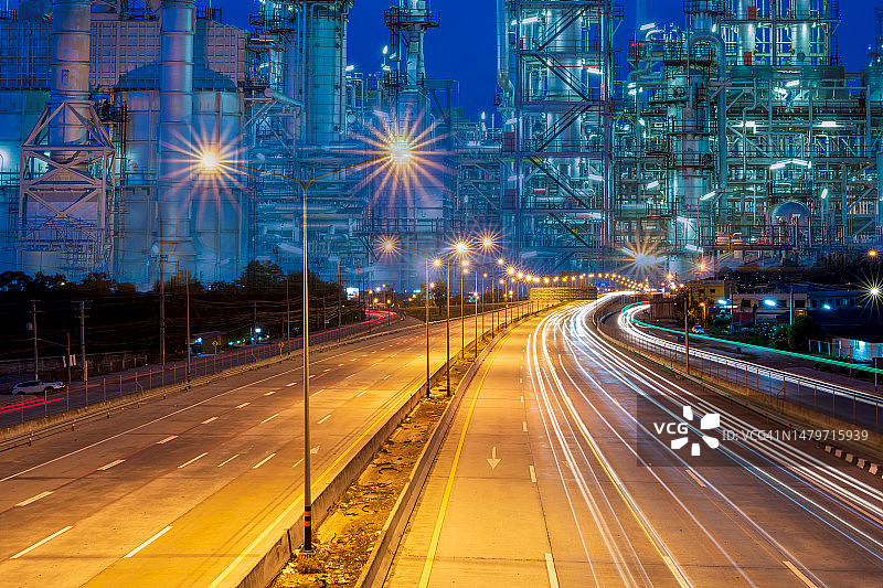 高速公路上美丽的路灯的双重曝光是由汽车尾灯和汽车前灯在暮色中与炼油厂工厂背景的曝光而产生的图片素材