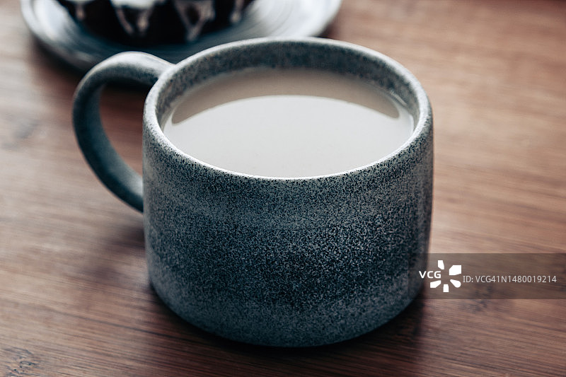 一杯加牛奶的咖啡。热巧克力放在木桌上的陶瓷杯里。图片素材