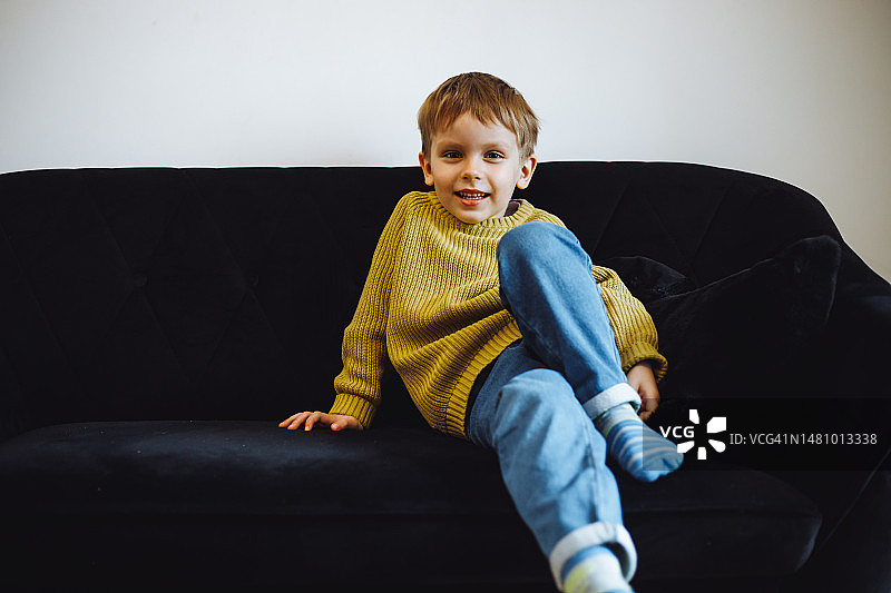 小男孩在灰色沙发上放松，沙发土豆周末活动图片素材