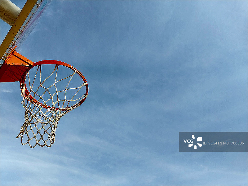 准备好与我们的充满活力的橙色篮球框和网在一个清晰的蓝天得分图片素材