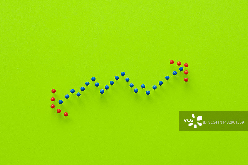 蓝色图钉代表绿色现代背景下的财务增长图表，红色箭头指向上下。图片素材