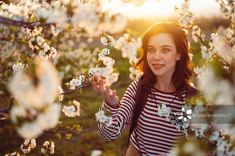 美丽的年轻女子在盛开的果园里享受着无忧无虑的春日图片素材