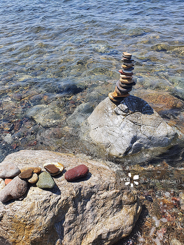 海滩上一堆平衡的石头对着大海图片素材