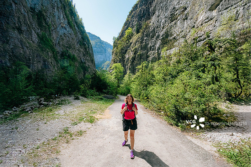 一位女徒步旅行者在峡谷中凝视着风景如画的景色。尤普沙尔基峡谷，尤普沙尔基峡谷，阿布哈兹图片素材