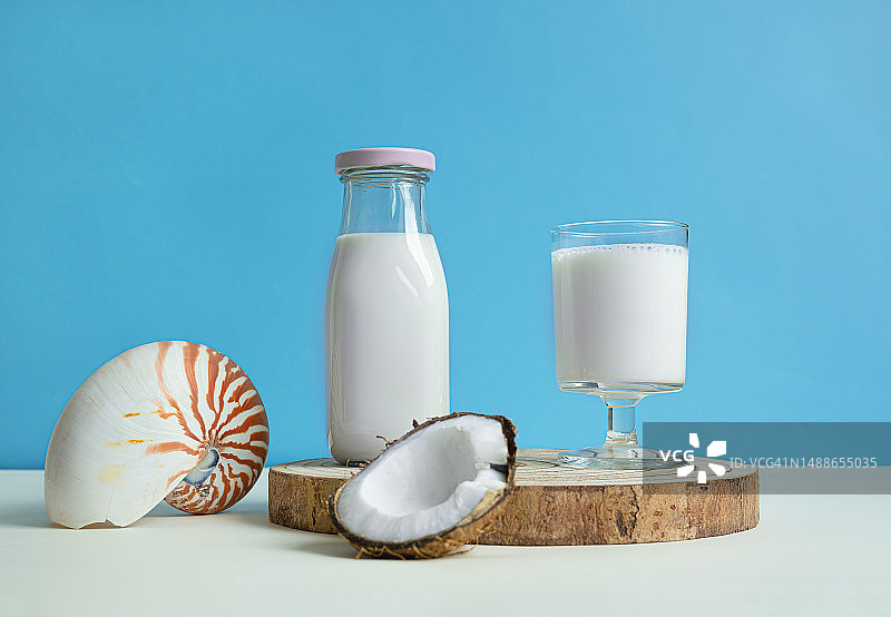 一杯和一瓶纯素椰奶，蓝色背景，产自法国图片素材