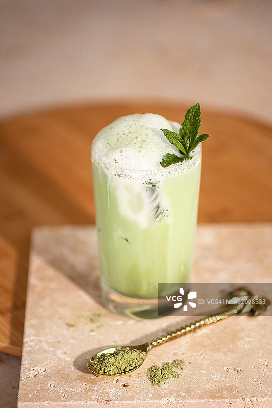 冰抹茶拿铁饮料，含有牛奶泡沫和绿色抹茶粉图片素材