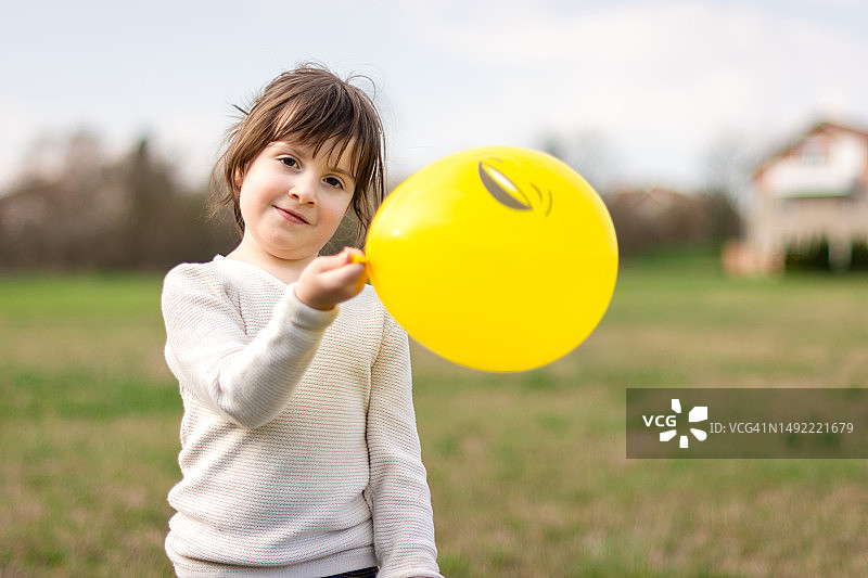 快乐的小女孩玩白色的黄色气球图片素材