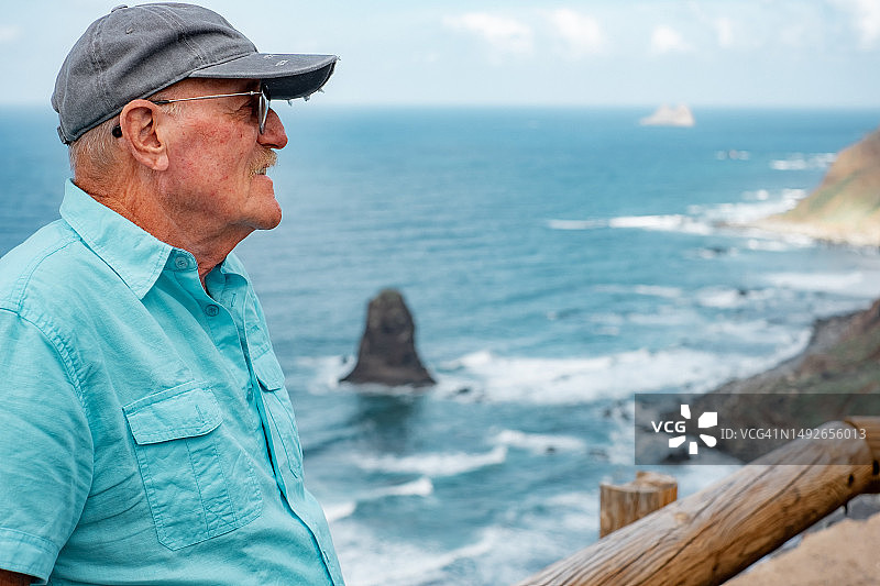 孤独的老人坐在海滩边享受旅行度假和大自然美景的肖像。海面地平线图片素材