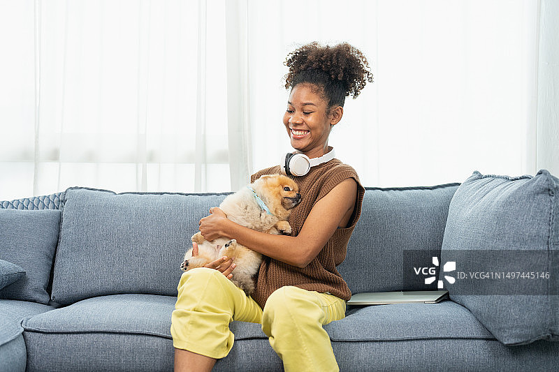 一个年轻女子在家里和她的小狗玩耍。图片素材
