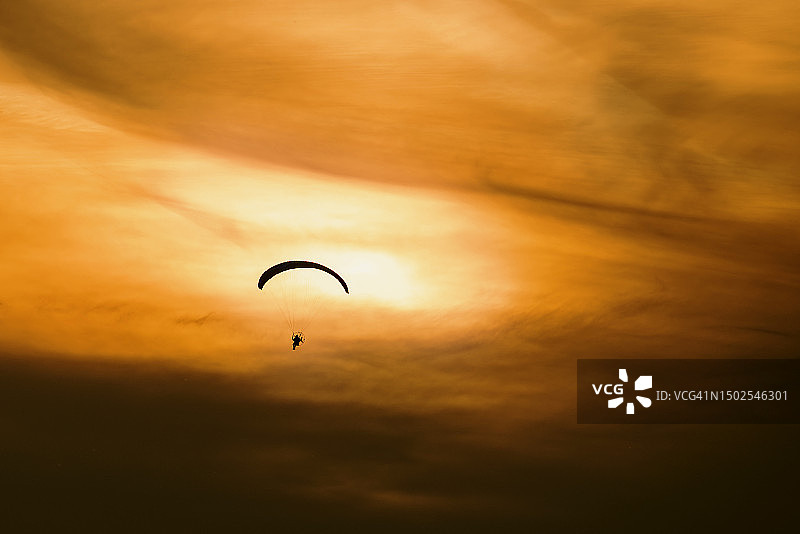 一个人的剪影滑翔伞对天空在日落，匈牙利图片素材