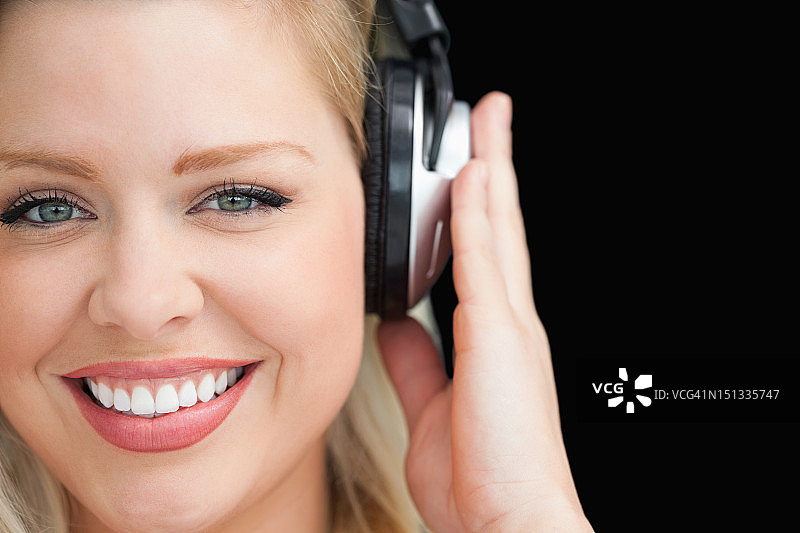 微笑的金发女人戴着耳机听音乐图片素材