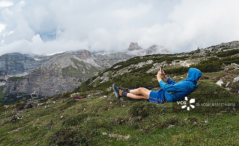 一名无法辨认的白人男子在徒步旅行中休息时用手机拍摄了拉瓦雷多多洛米蒂山脉的照片图片素材