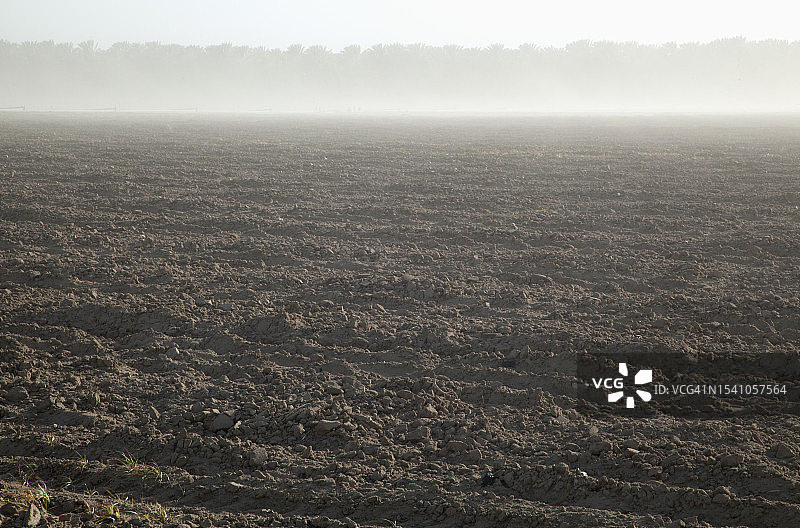 在一个多风多尘的日子里，准备播种的犁过的田地。图片素材