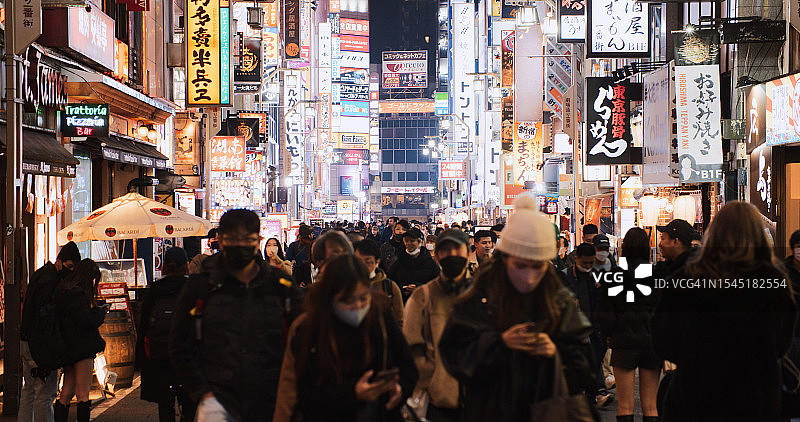日本人，亚洲游客晚上走在东京新宿歌舞伎町红灯区的街道上。日本旅游景点，旅游地标，亚洲夜生活，城市生活理念图片素材