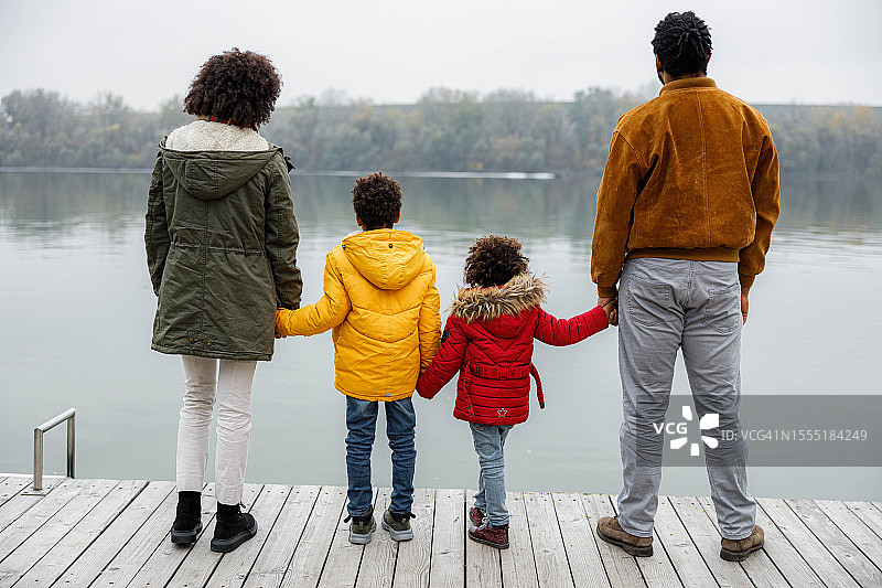 一个黑人家庭在河边码头的后景。图片素材