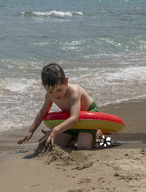 小男孩拿着充气戒指在沙滩上玩耍图片素材
