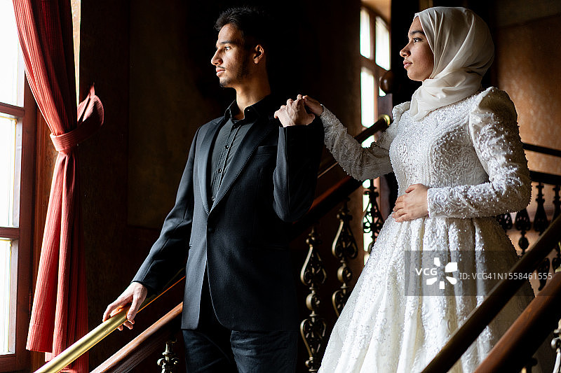 穆斯林夫妇在他们的婚礼当天，电影般的灯光，手牵着手图片素材