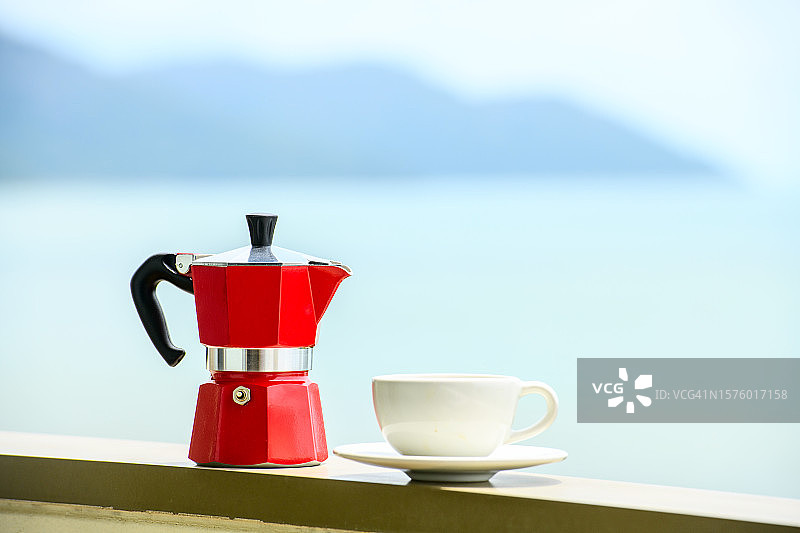 一个鲜红色的咖啡机和一个带海景的杯子图片素材