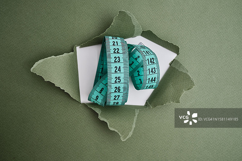 浅色背景上的绿色卷尺。测量长度和体积的工具。用于测量服装行业或人体体积的卷尺图片素材