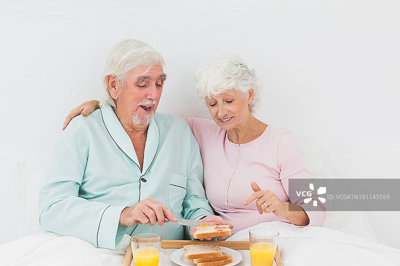 幸福的夫妇在床上吃早餐图片素材
