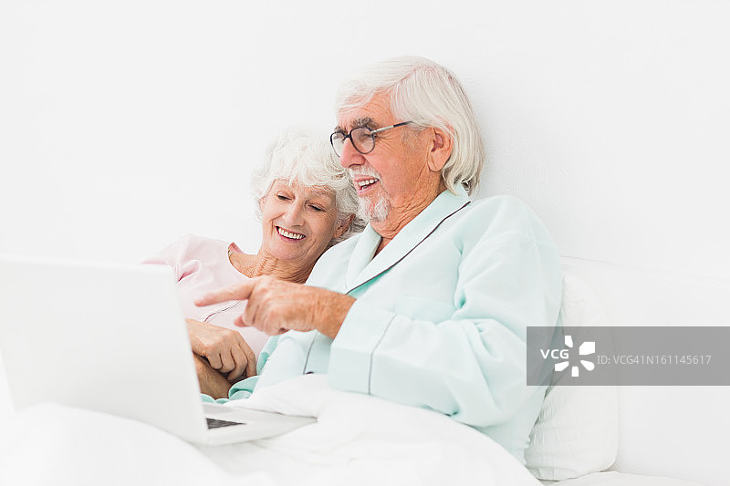 幸福的夫妇在床上使用笔记本电脑图片素材
