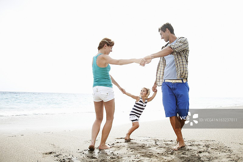 父母和女儿(4-5岁)在沙滩上玩耍图片素材
