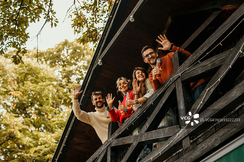 一群朋友一起在森林小屋的阳台上闲逛。图片素材