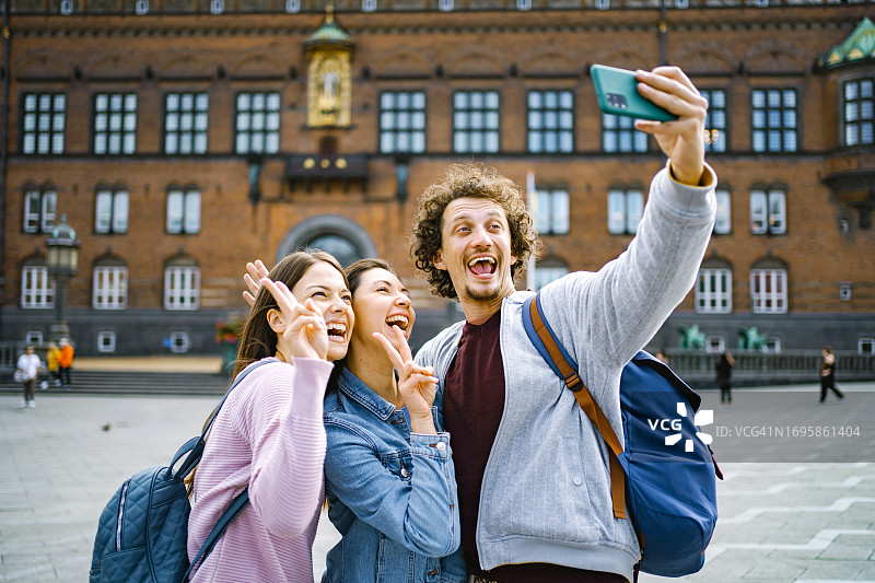 三个面带微笑的游客在探索哥本哈根市时自拍图片素材