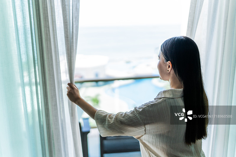 一个女人在酒店拉开卧室的窗帘图片素材