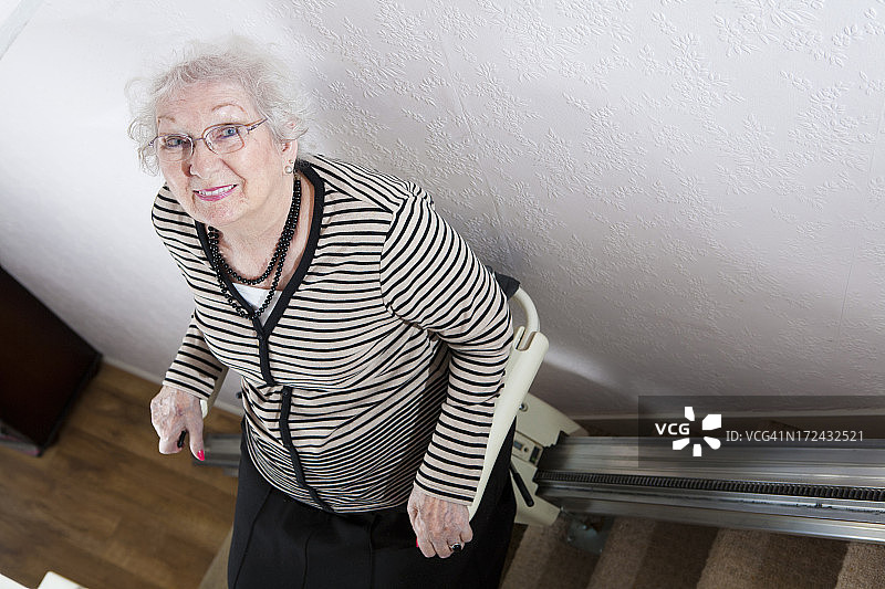 老妇人使用楼梯升降机来帮助她的残疾图片素材