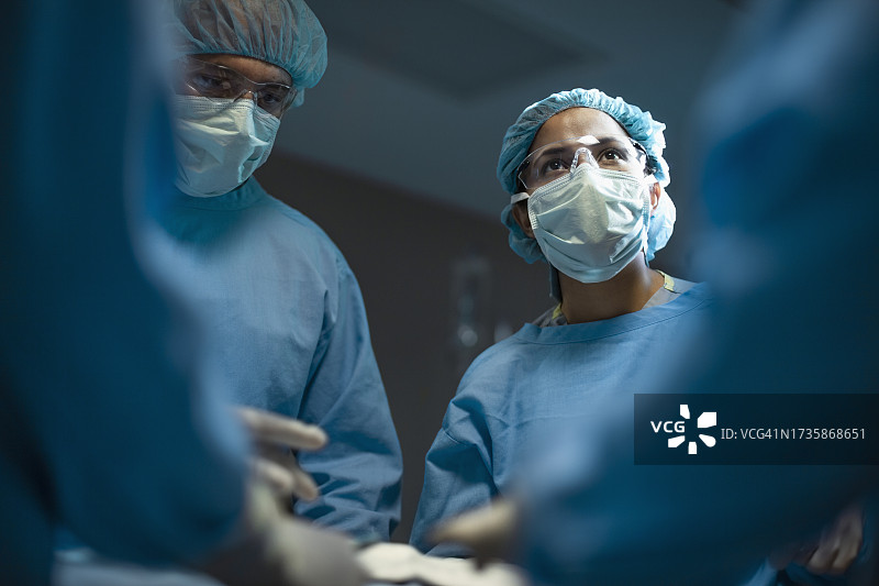 西班牙裔医学专业医生护士在医院与同事进行手术过程中向上看图片素材