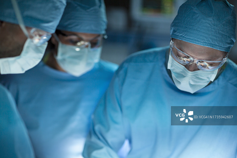 穿着防护服的医生和护士在医院外科手术室与医疗专业团队一起俯视病人的正面照片图片素材
