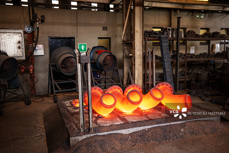 在钢铁铸造厂经过热处理的亮橙色钢管图片素材