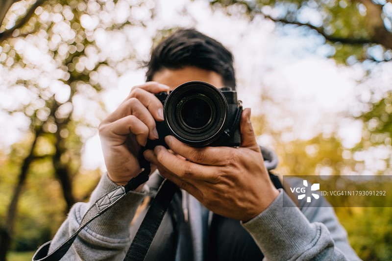 一名男子在秋天的森林里使用数码单反相机图片素材