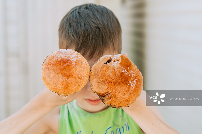 男孩拿着两个大蘑菇靠近他的眼睛，特写。有蘑菇和一个11岁小孩的有趣照片图片素材