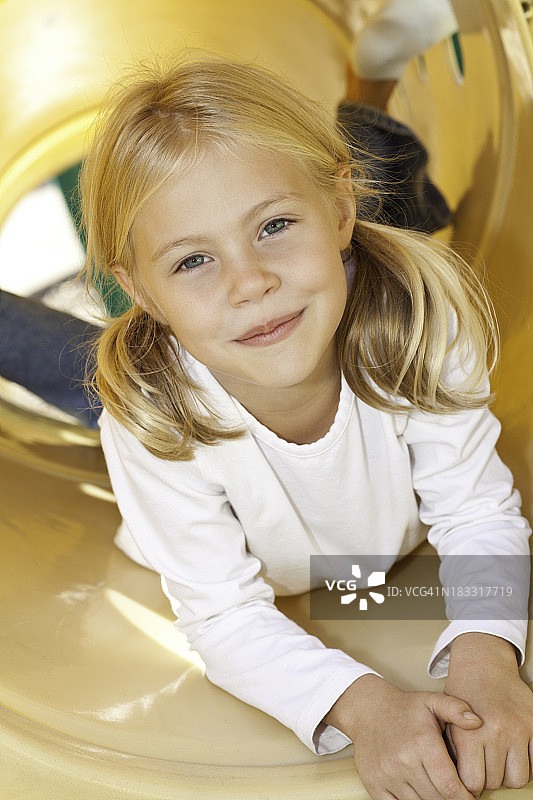 快乐的小女孩在一个管子在操场上图片素材