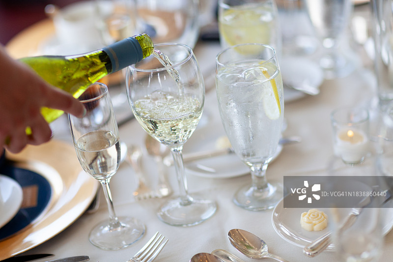 在正式的餐桌上倒白葡萄酒图片素材