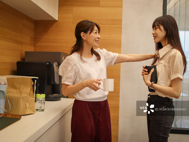 两个女职员在办公室旁边的茶室里喝茶聊天。年长的妇女鼓励年轻的妇女。图片素材