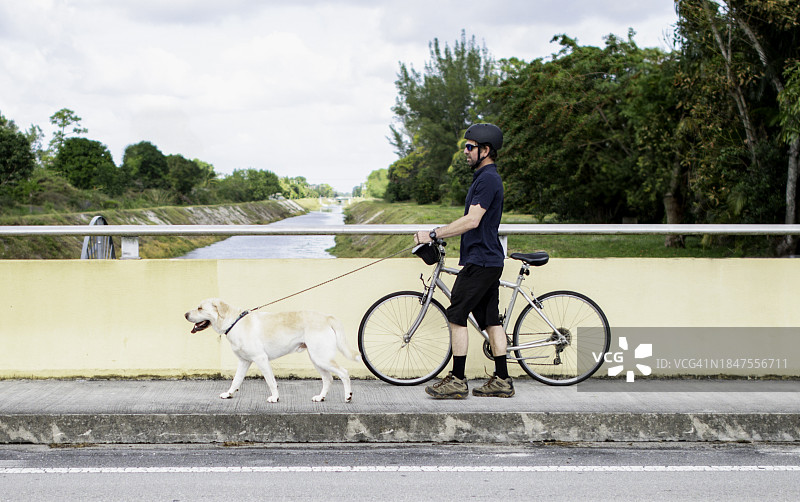 骑自行车的人带着狗，骑自行车的人带着他的大品种狗散步图片素材