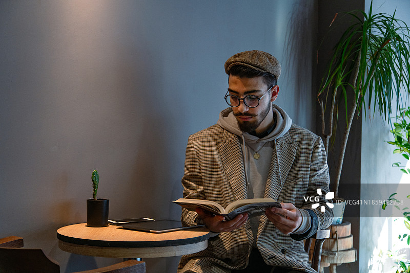 戴着眼镜的年轻英俊男子在咖啡店消磨时间。图片素材