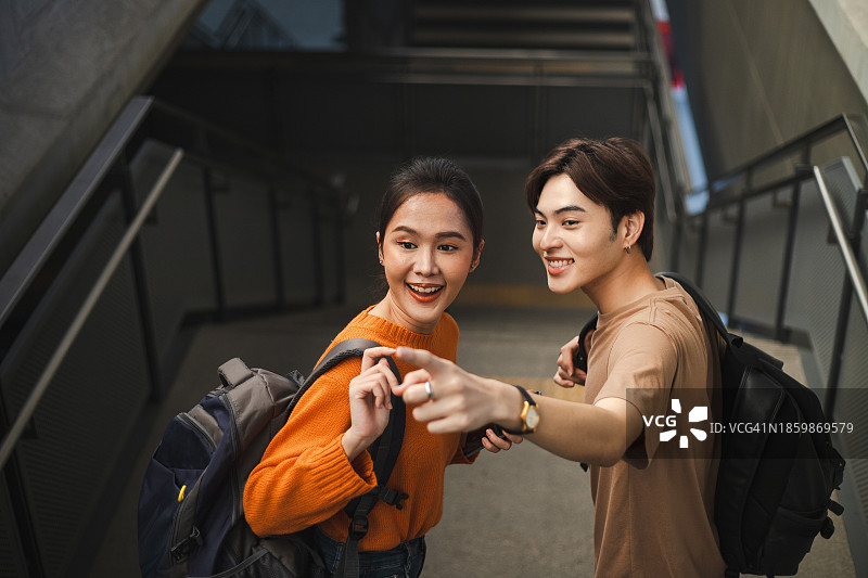 可爱的夫妇用智能手机进行GPS导航后站在火车站图片素材