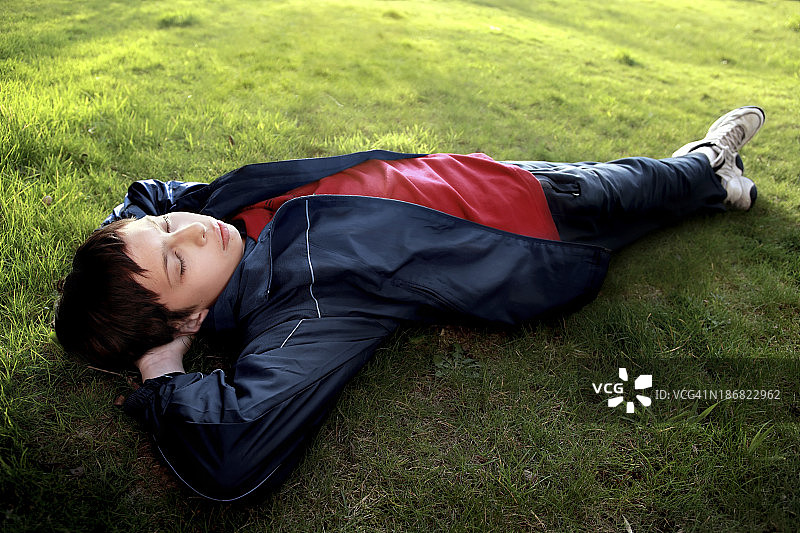 男孩睡在绿色的草地上图片素材