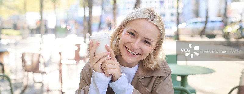 坐在路边咖啡馆里微笑的年轻女子的肖像图片素材